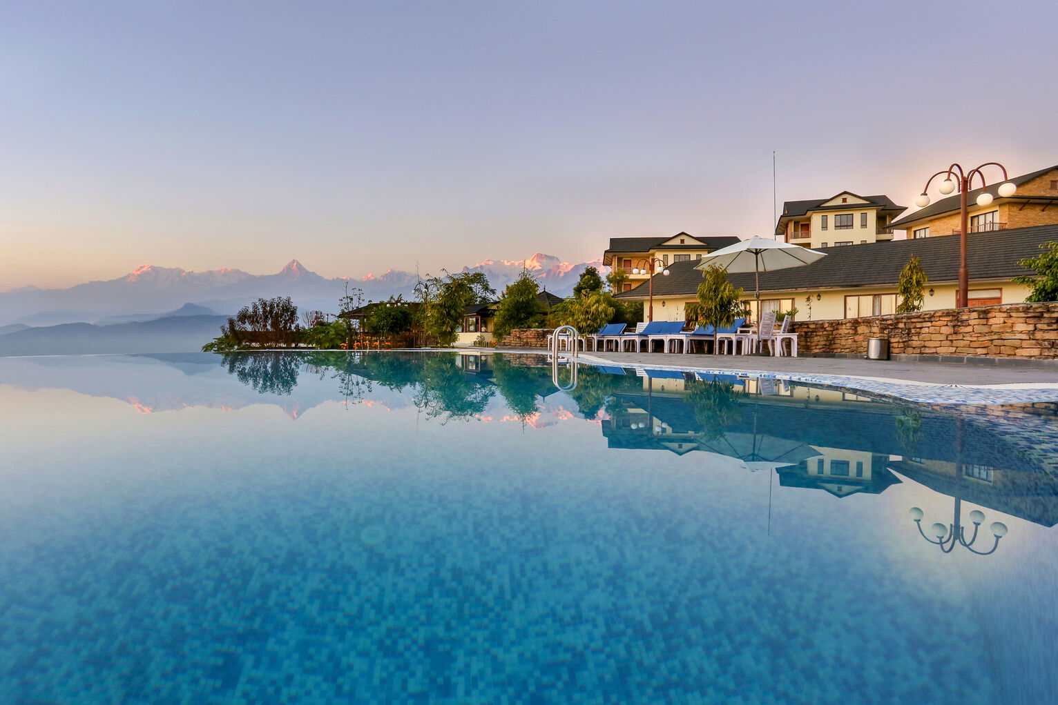 The infinity pool at Rupakot Resort reflecting the villas and the mountains
